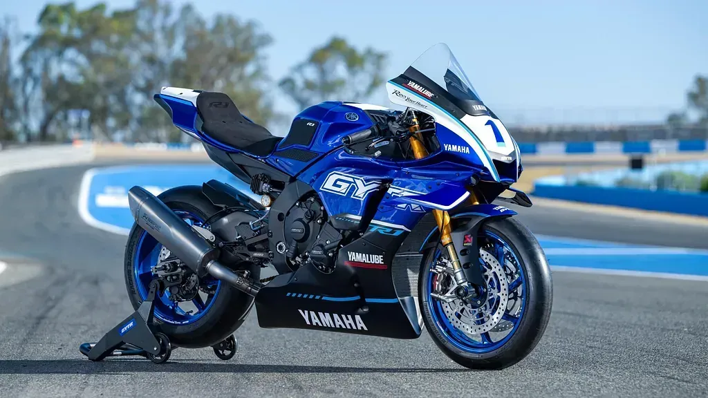 Una motocicleta azul y blanca está estacionada al costado de una pista de carreras.