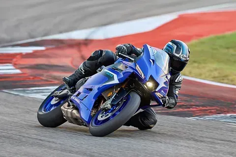 Un hombre conduce una motocicleta azul en una pista de carreras.