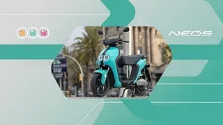 Un scooter azul está estacionado al costado de la carretera en una ciudad.