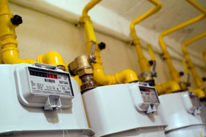 Una fila de medidores de gas y tuberías amarillas en una pared.