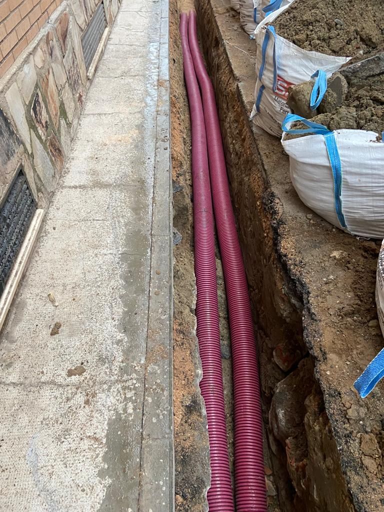Un par de mangueras rojas tiradas en la tierra al lado de una acera.