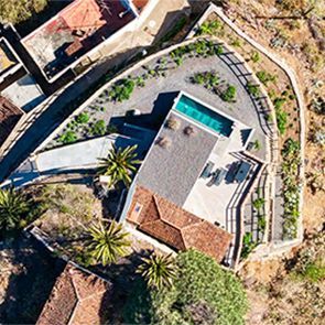 Una vista aérea de una casa con piscina y palmeras.