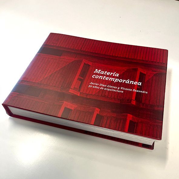Un libro rojo titulado Materia Contemporánea está sobre una mesa blanca.