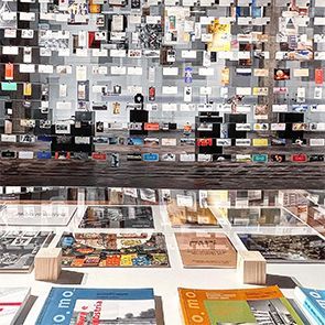 Una mesa con muchas revistas encima y una pared detrás.
