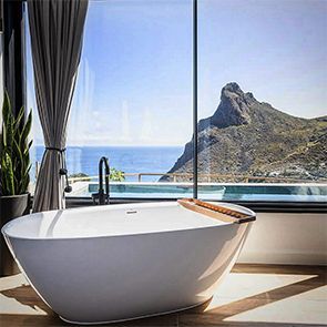 Una bañera en un baño con vista al mar y a las montañas.