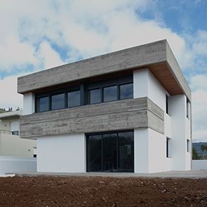 Una casa blanca con muchas ventanas está situada en la cima de una colina de tierra.