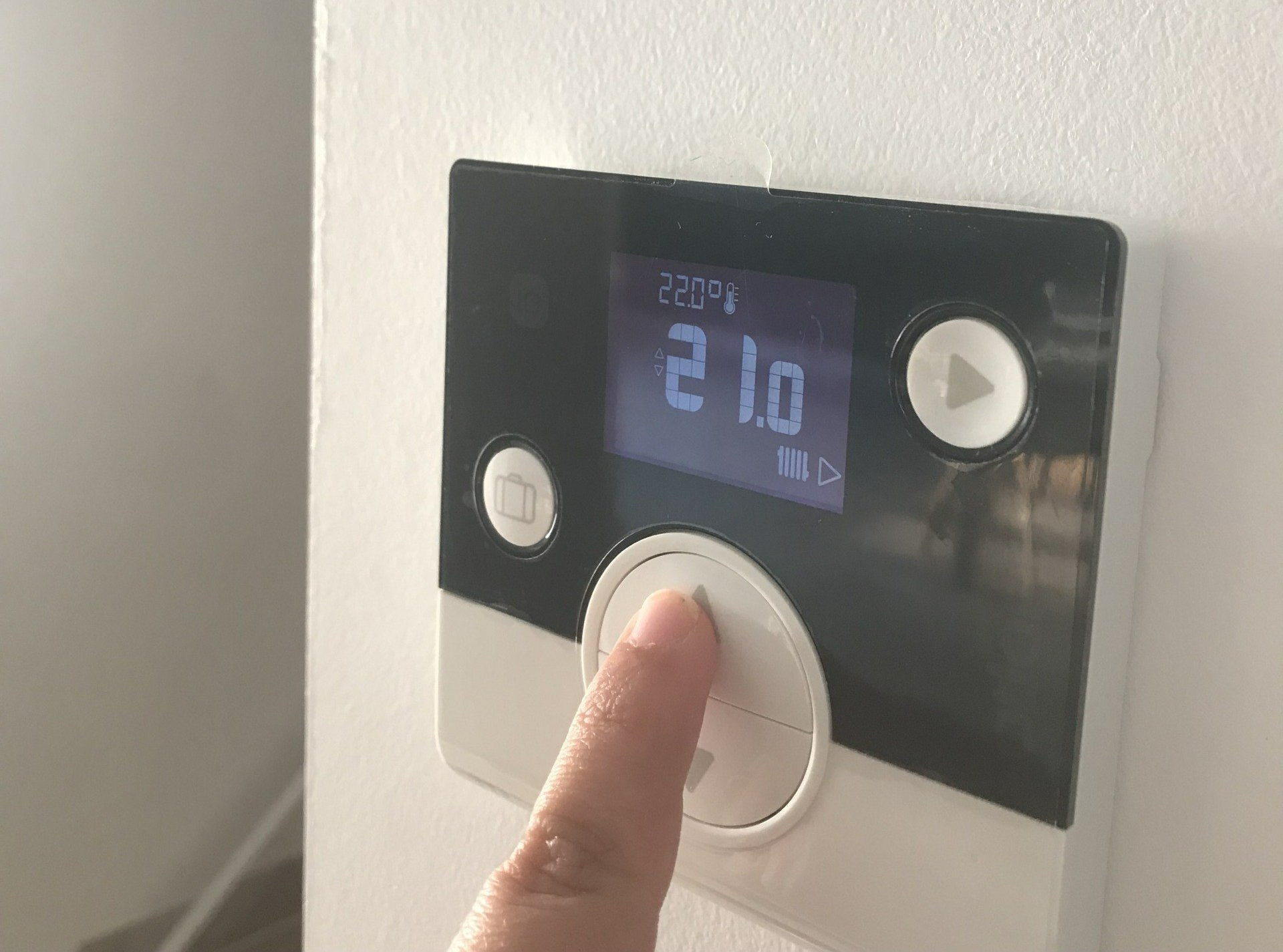 Doigt touchant un thermostat.