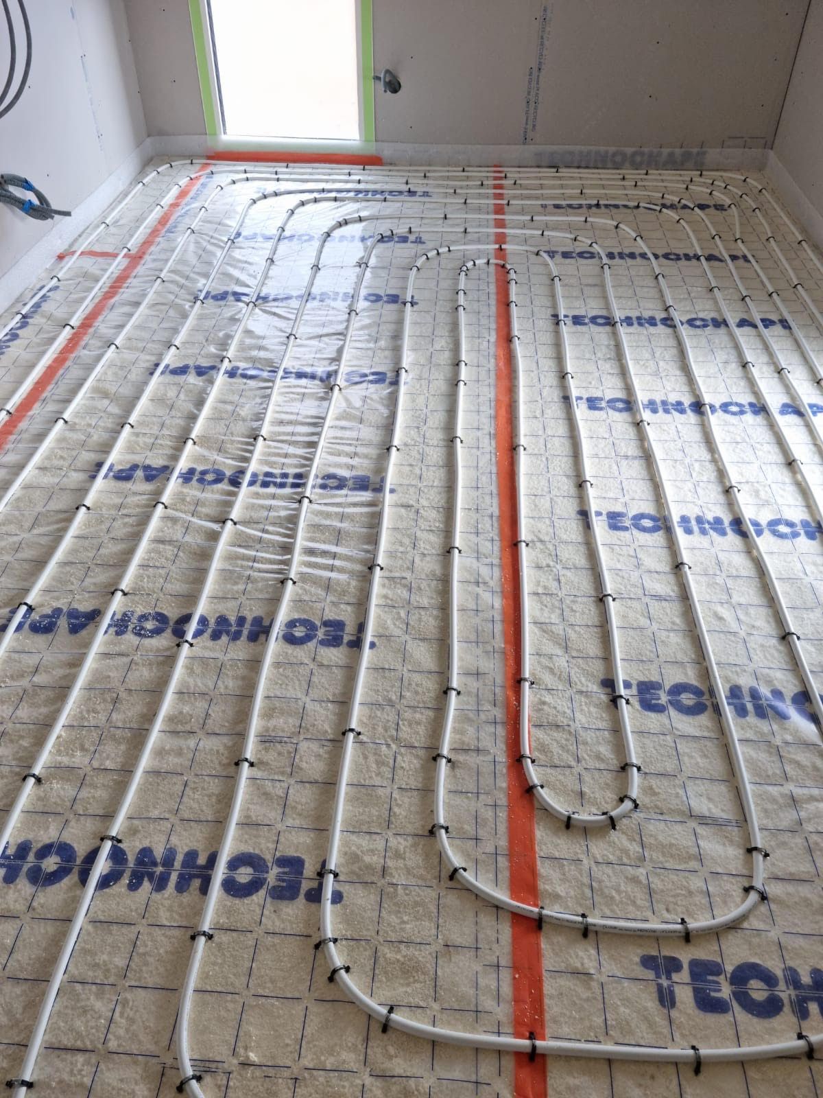 Pose de plancher chauffant avec les tuyaux chauffants sur le sol. 