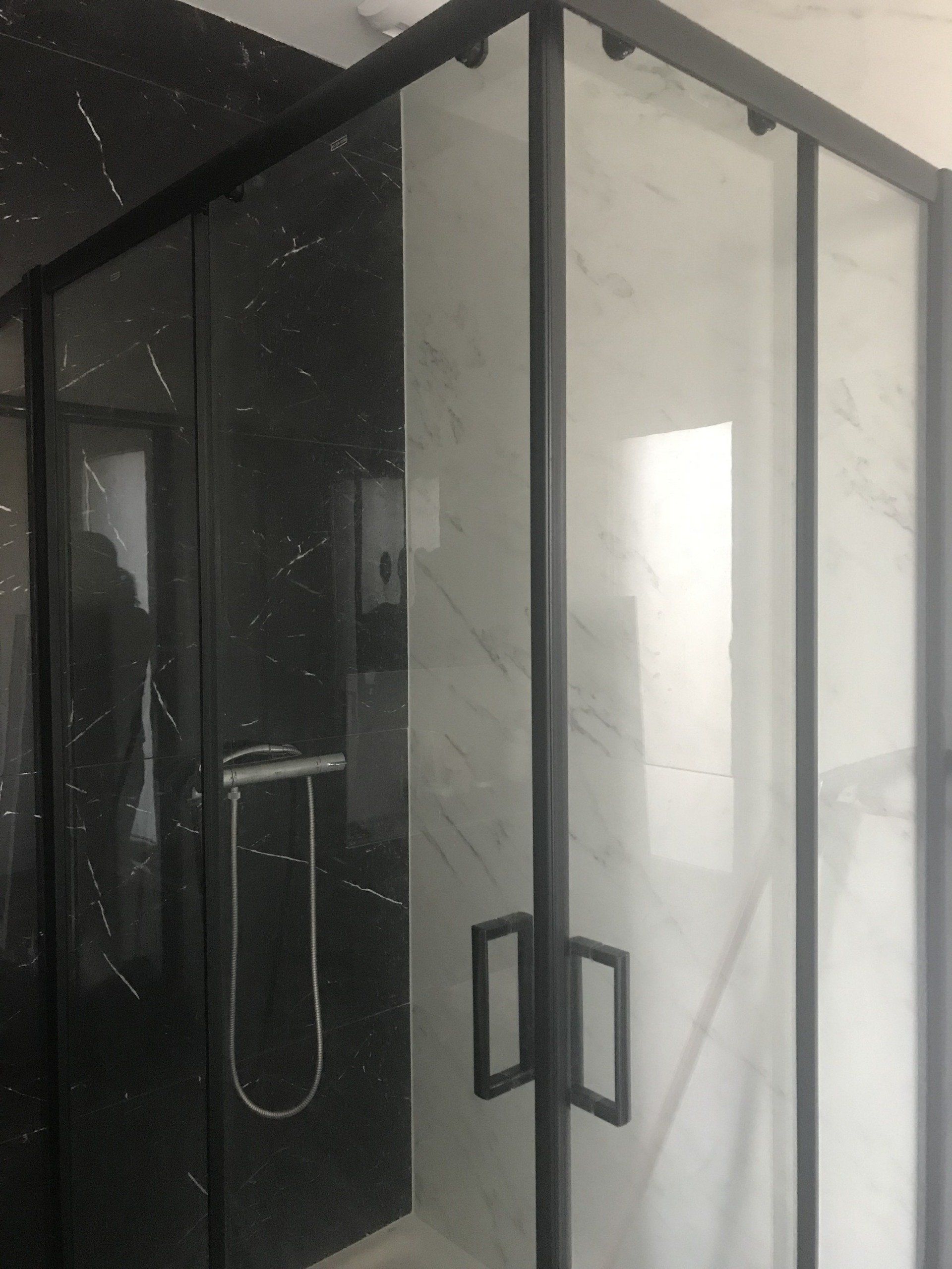 Installation de cabine de douche avec carrelage blanc et noir effet marbre.