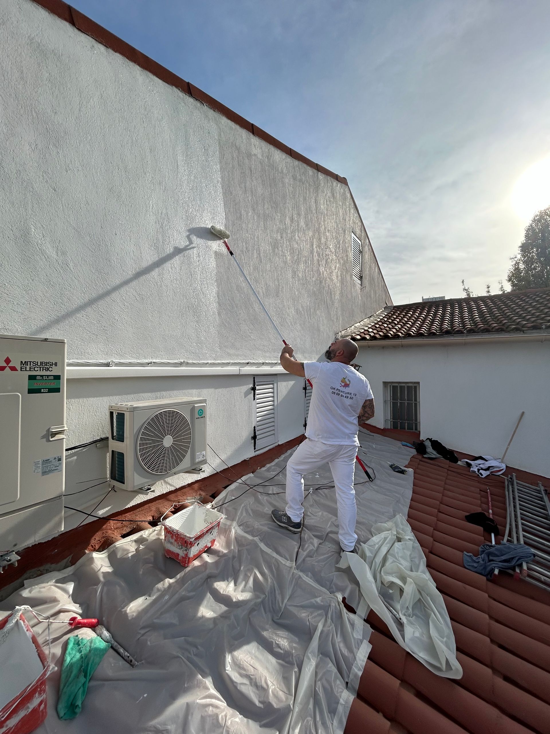 Peintre qui peint un mur extérieur de maison