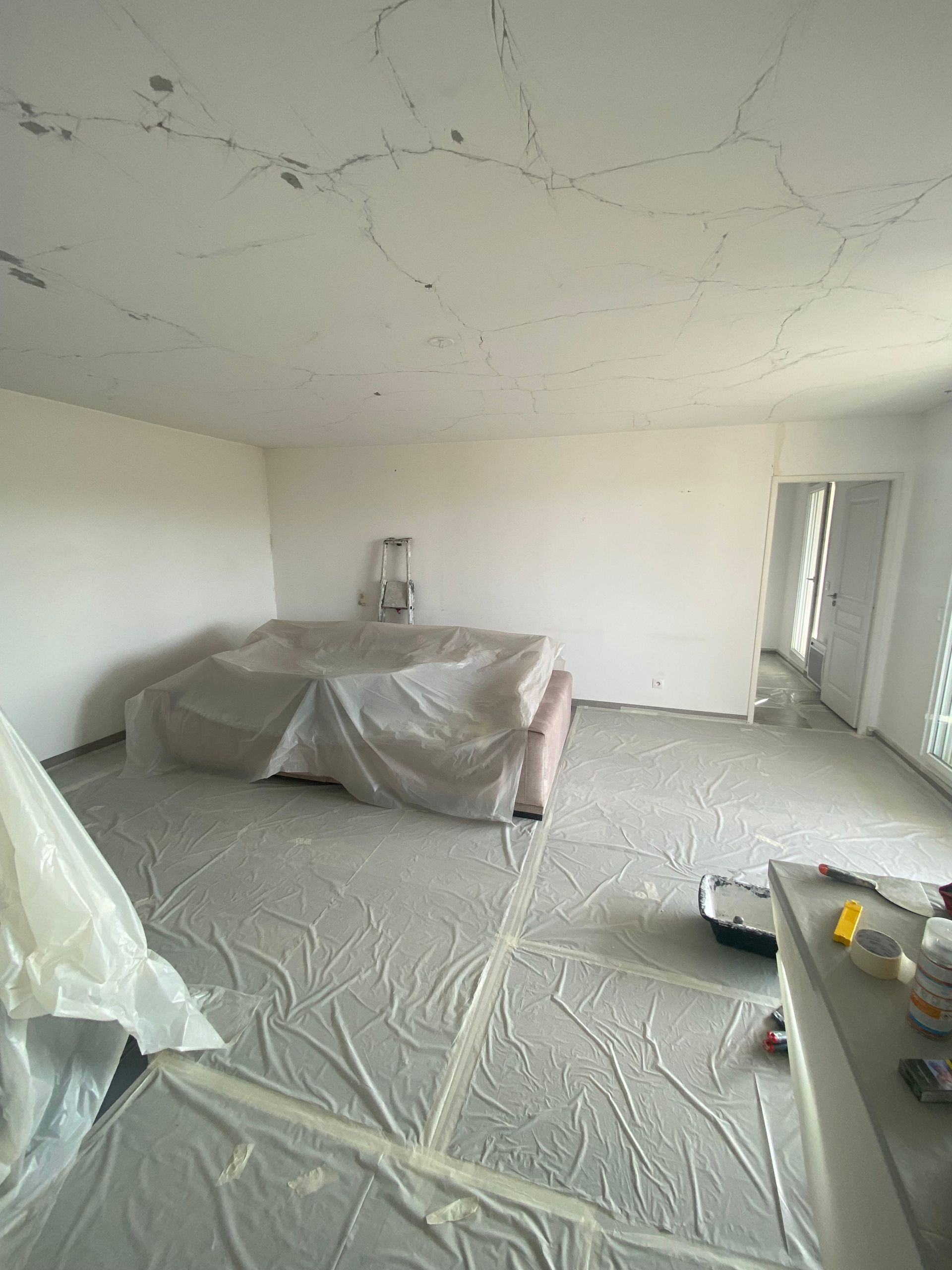 Salon à rénover avec protection des sols et du canapé