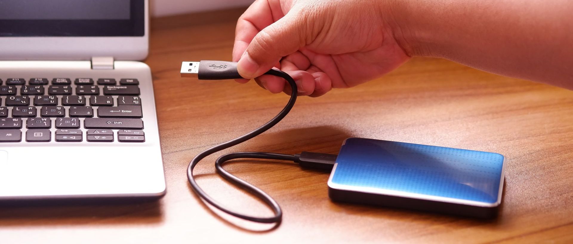 Une personne qui branche un disque dur externe à un ordinateur portable