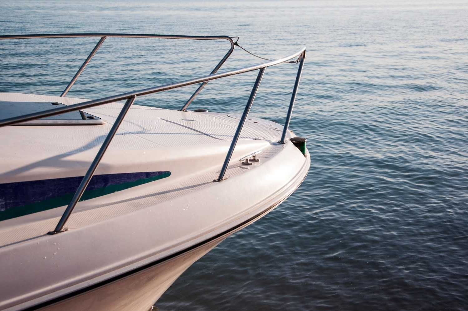 Interior de un yate de lujo con asientos de cuero color crema, mesa de madera y alfombra azul.