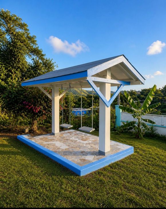 Two swings mall white-and-blue pavilion with a tiled floor in a sunny grassy yard at Chenko Villas + Rental Cars