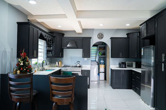 Modern kitchen with dark cabinets, island seating, and stainless steel appliances at Chenko Villas + Rental Cars