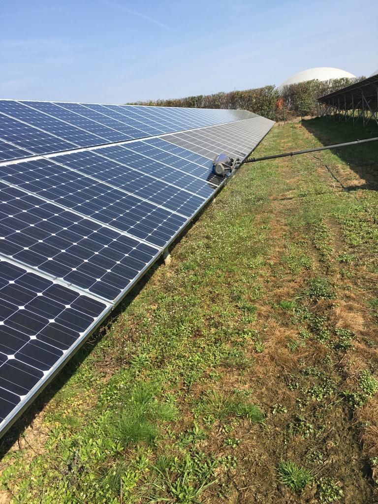 Paneles solares en un campo, absorbiendo la luz solar. Césped verde y cielo azul de fondo.