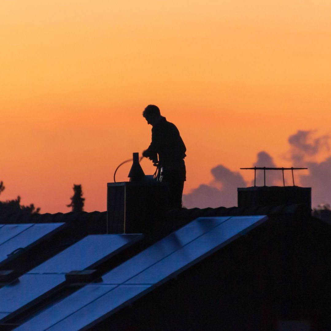 Homme en train de ramoner une cheminée au coucher du soleil