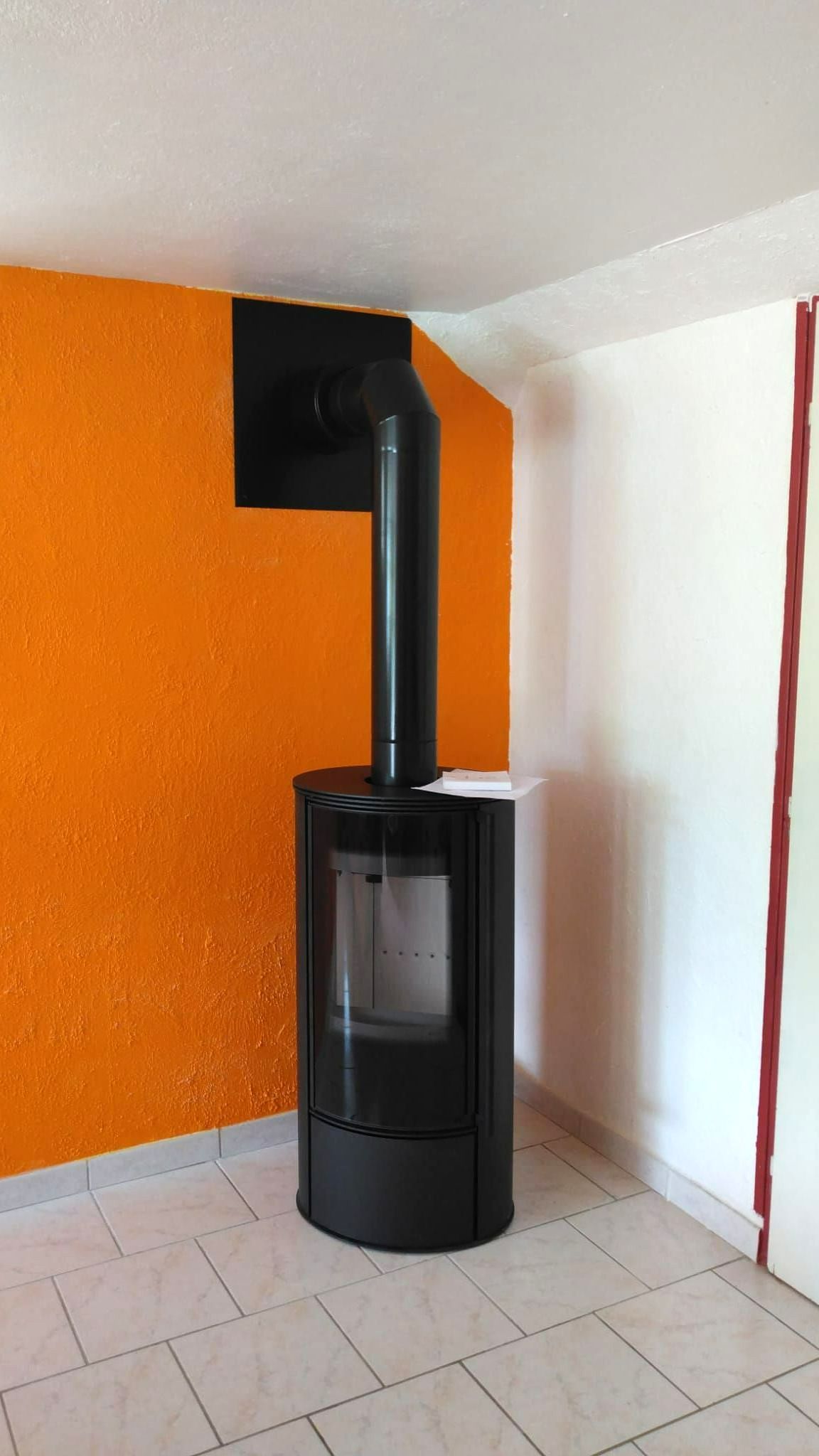 Poêle en fonctionnement devant un mur orange