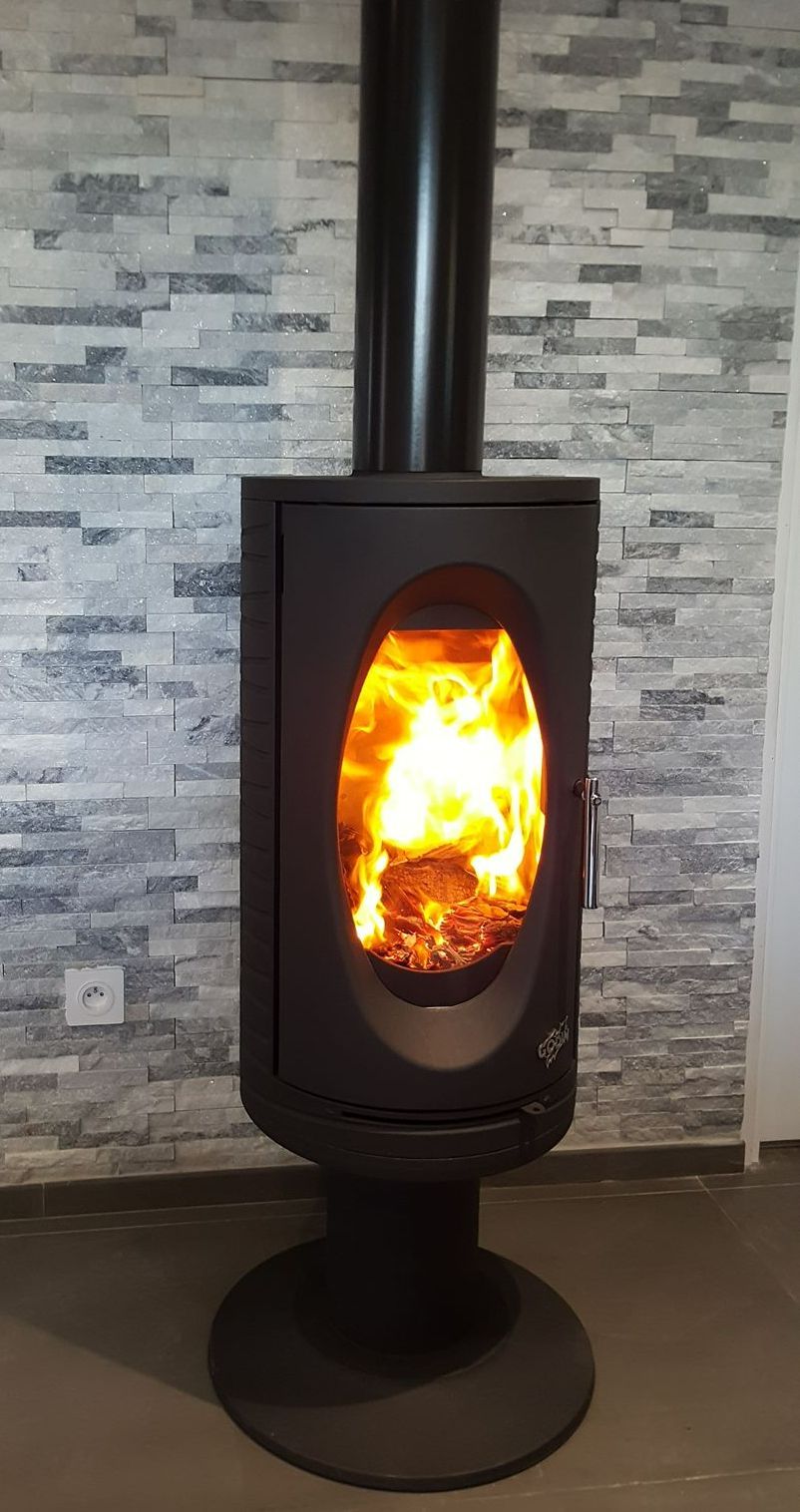 Poêle allumé devant un mur en pierre grise