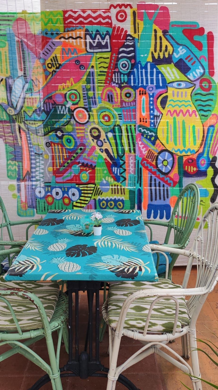 Un comedor con una mesa y sillas y un mural colorido en la pared.