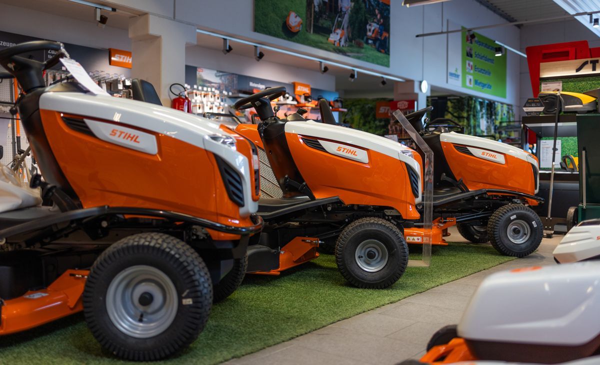 In einem Geschäft stehen mehrere Rasenmäher aufgereiht.