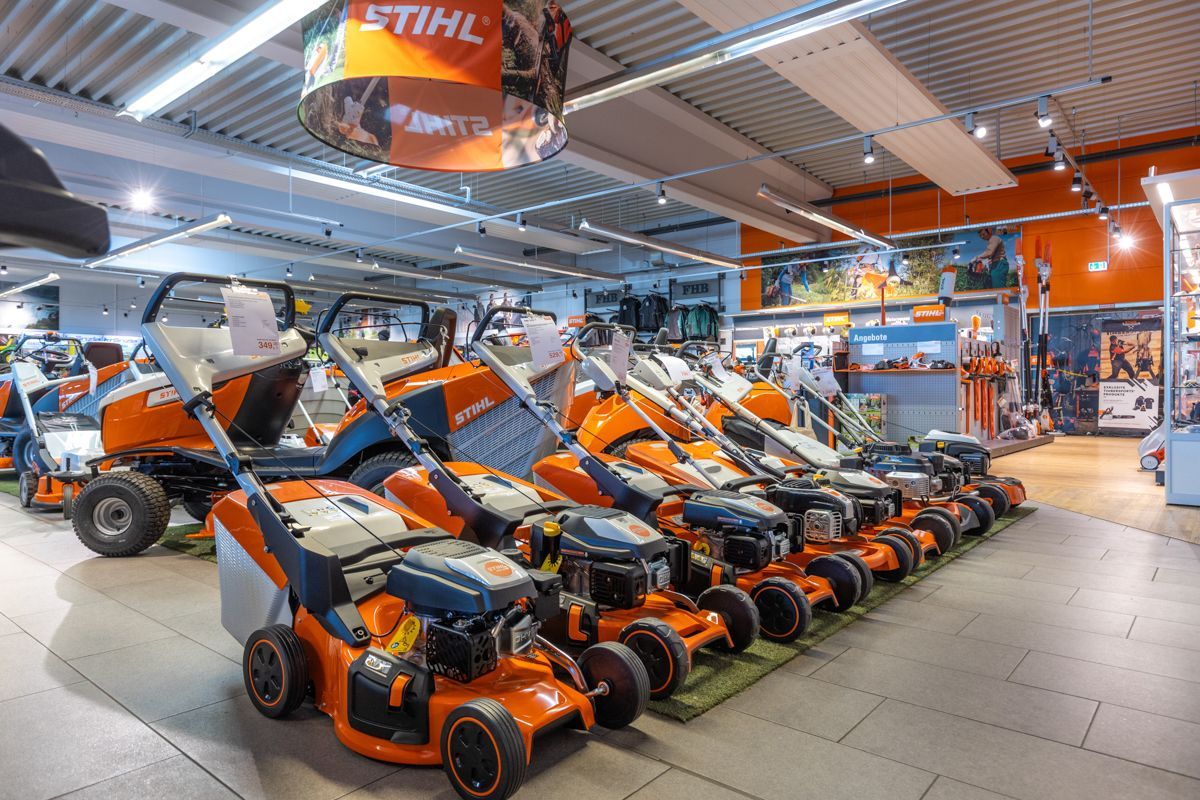 In einem Geschäft stehen mehrere Rasenmäher aufgereiht.