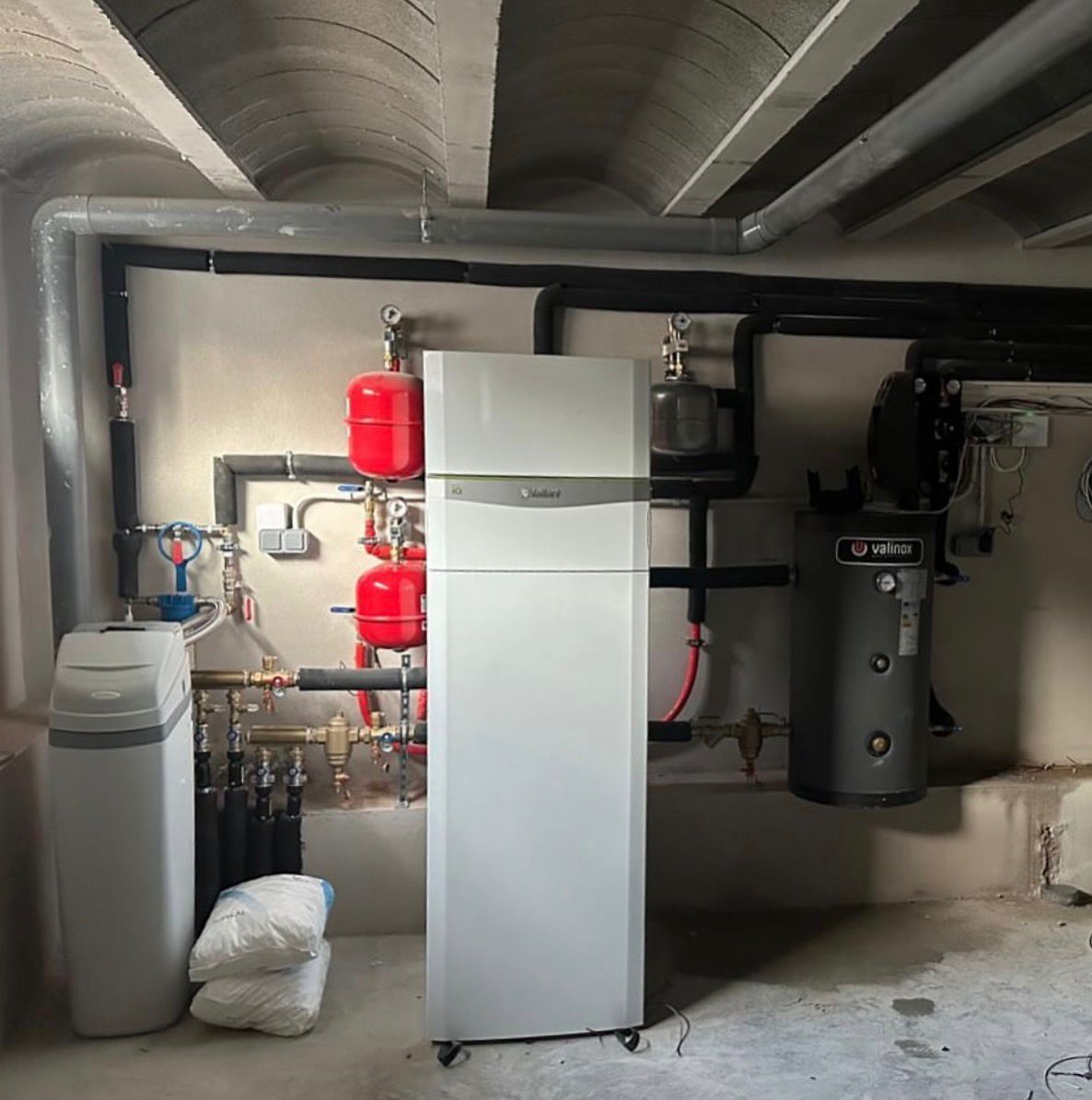 Cuarto de servicio con refrigerador, suavizador de agua, tanques, tuberías y otros equipos. Paredes y techo de hormigón.