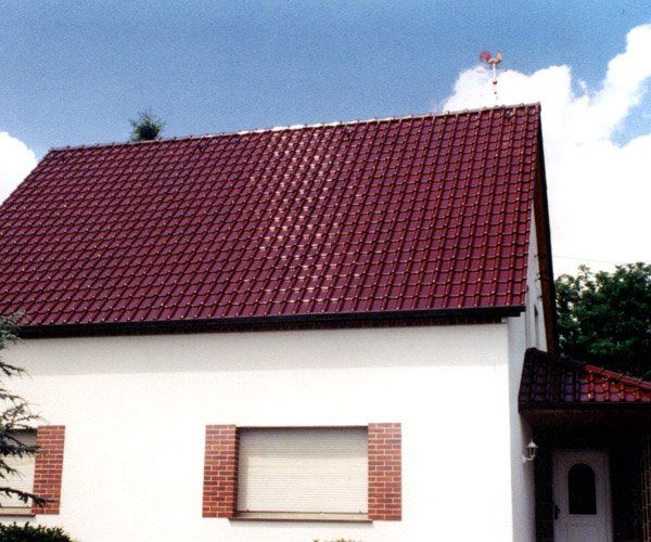 Weißes Haus mit roten Ziegeln auf dem Dach, gelegt durch die Firma Busch Ramona