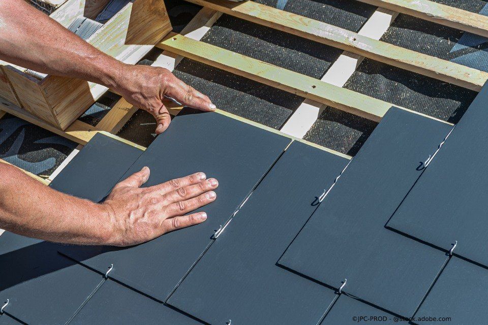 Mitarbeiter der Firma Busch Ramona legt Schieferplatten auf ein Dach