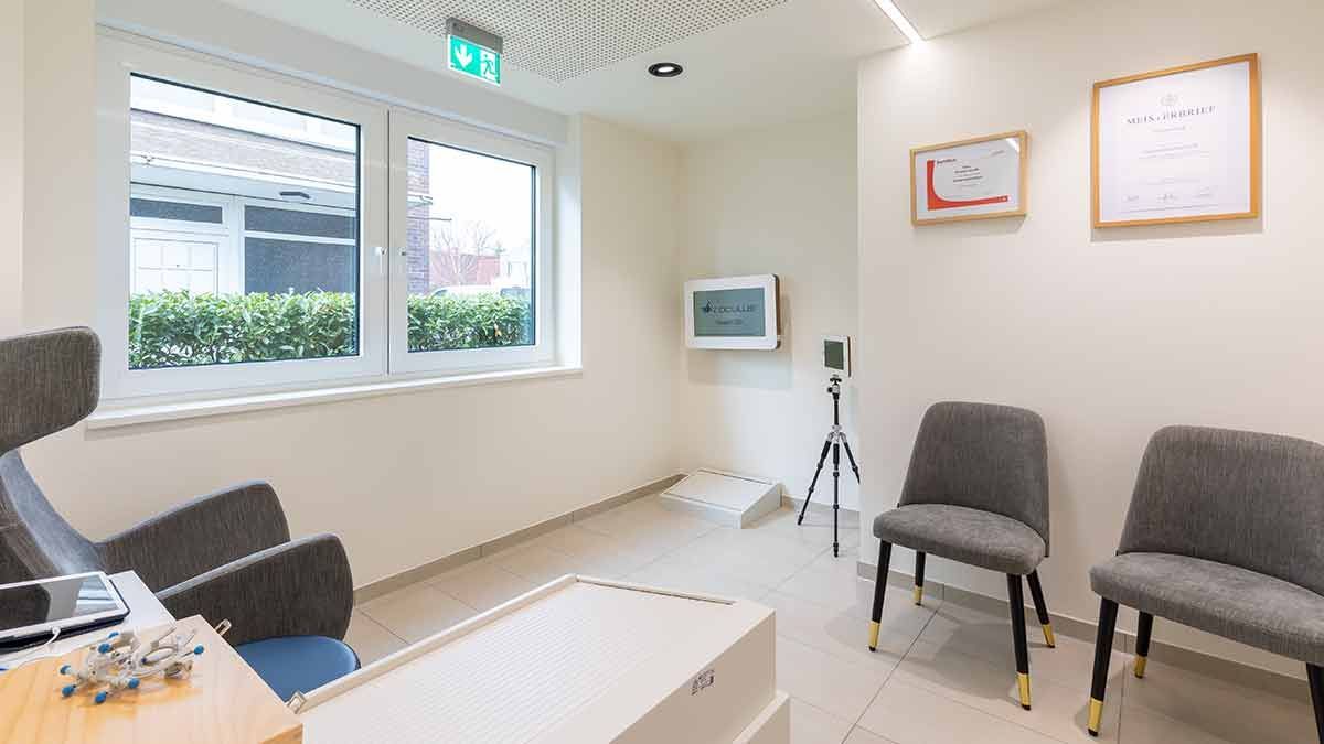 Ein Wartezimmer mit Stühlen, einem Tisch und einem Fernseher.