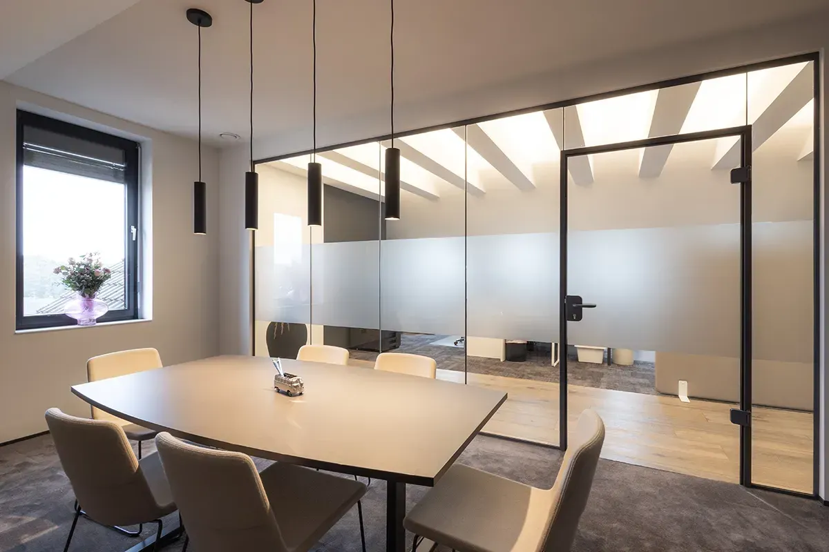 Ein Konferenzraum mit Tisch und Stühlen und einer Glaswand.