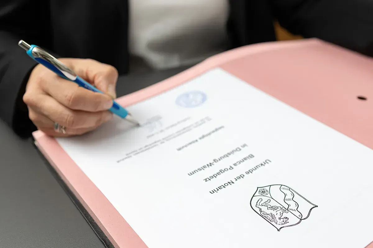 Eine Person schreibt mit einem Stift auf ein Blatt Papier.