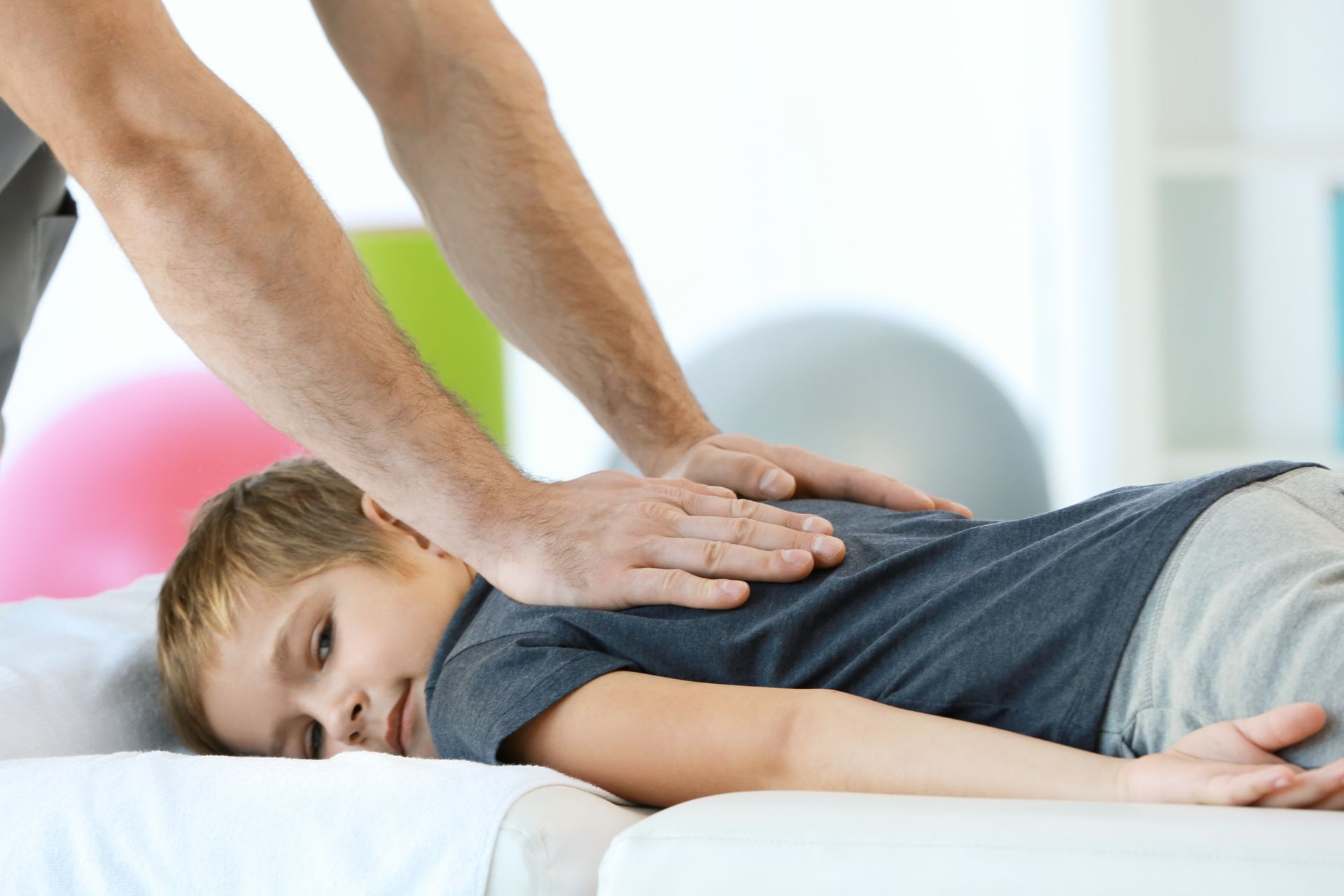 Eine Frau entspannt sich während einer Spa-Behandlung auf einer Massageliege, warmes Kerzenlicht liegt in der Nähe.