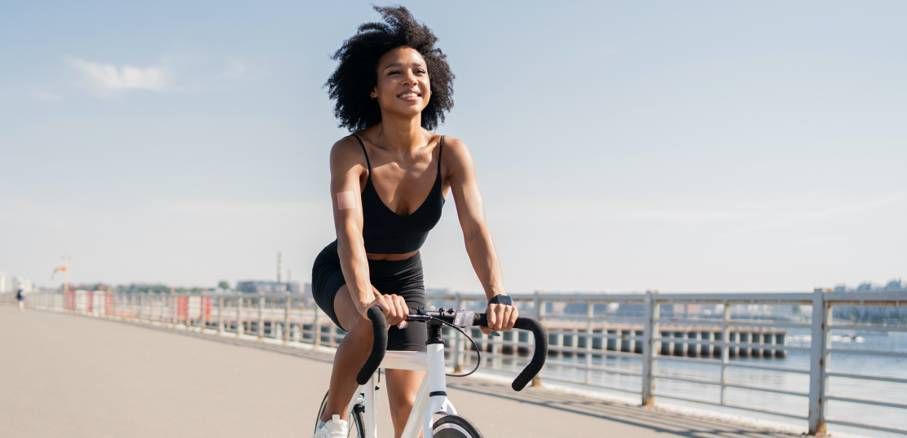Radfahrer fährt an einem sonnigen Tag auf einer Strandpromenade neben einem Geländer.