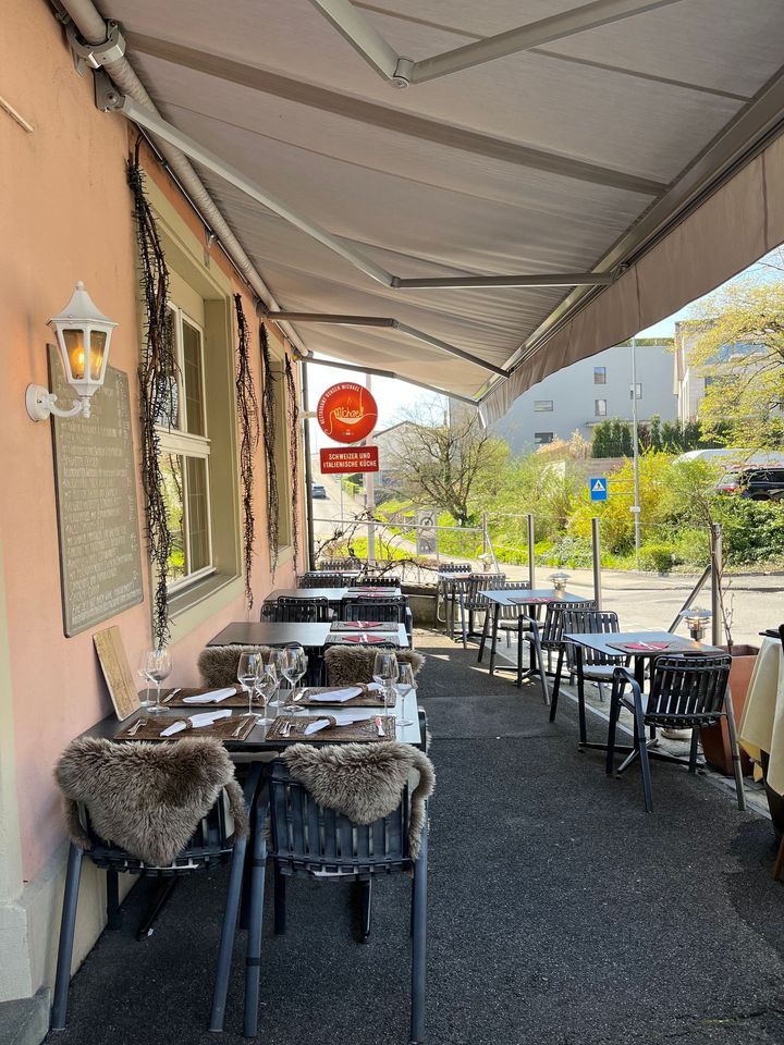 Ein rosafarbenes, zweistöckiges Restaurant namens „Restaurant Ochsen“ mit dunkelgrünen Fensterläden an einer Straßenecke.
