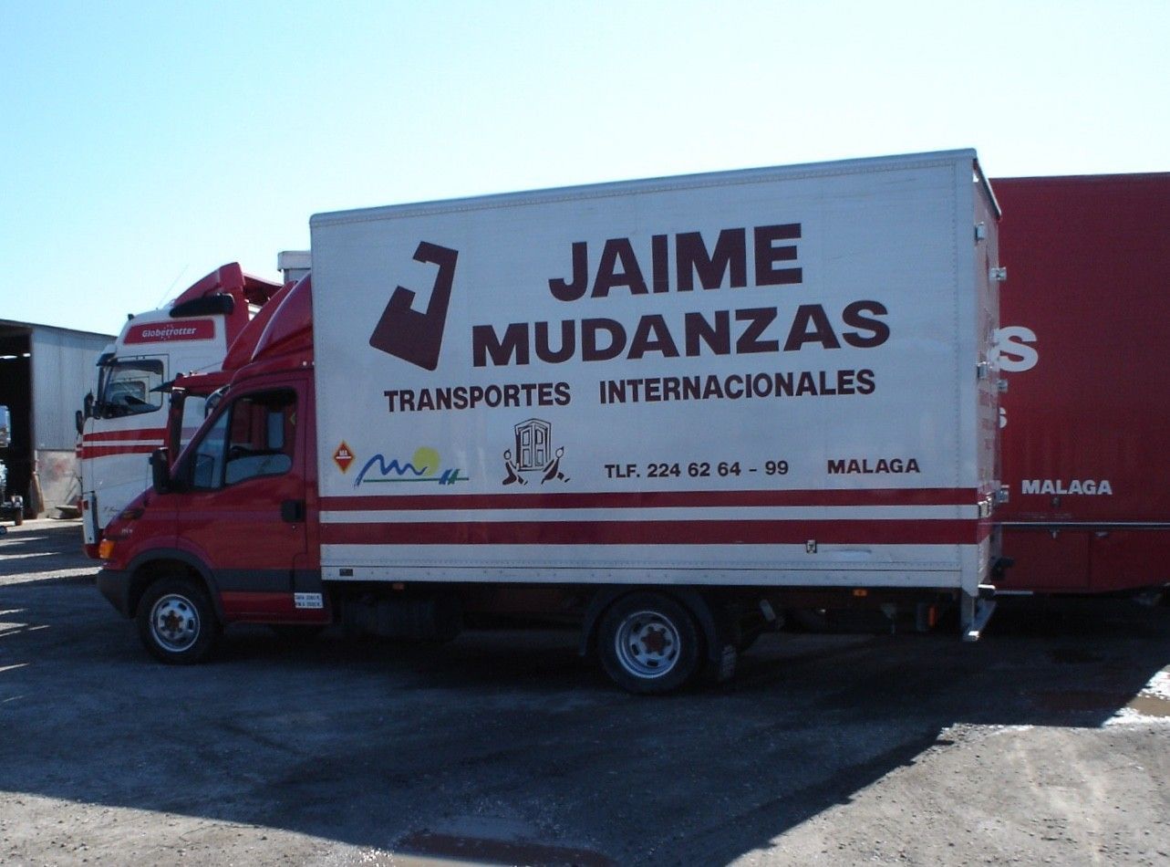 Camión de mudanzas rojo con letrero de “JAIME MUDANZAS” estacionado al aire libre en un día soleado.