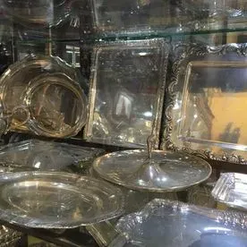 Una vitrina llena de platos de plata y espejos.