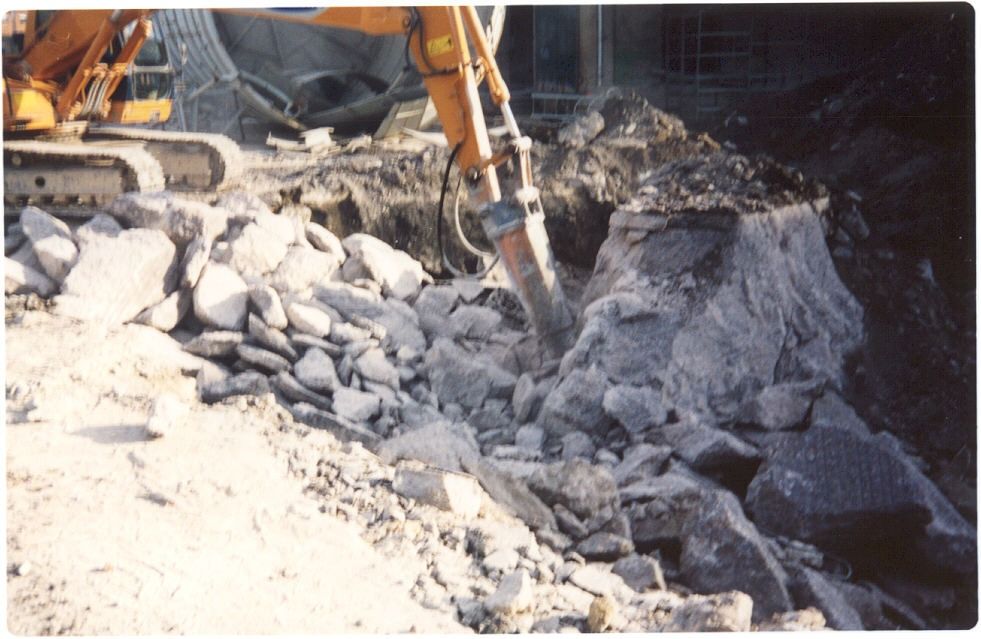 Una excavadora amarilla está cavando en una pila de rocas.
