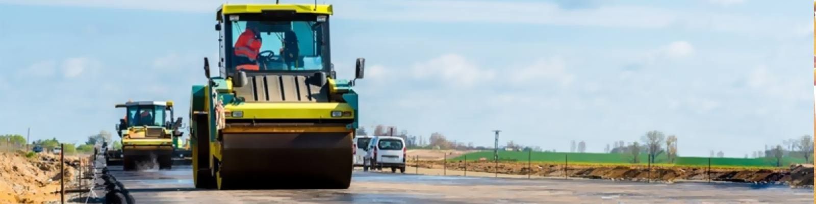 Un par de vehículos de construcción circulan por una carretera.