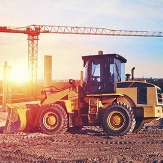 Una excavadora está estacionada en un sitio de construcción al lado de una grúa.