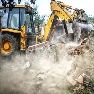 Una excavadora amarilla está demoliendo un edificio.