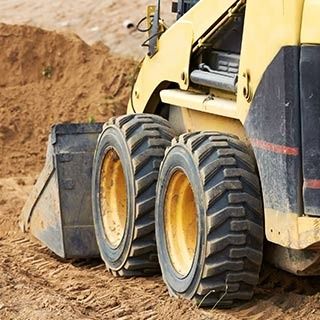 Una excavadora amarilla está estancada en el suelo en un sitio de construcción