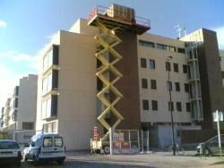 Un elevador de tijera está situado encima de un edificio.