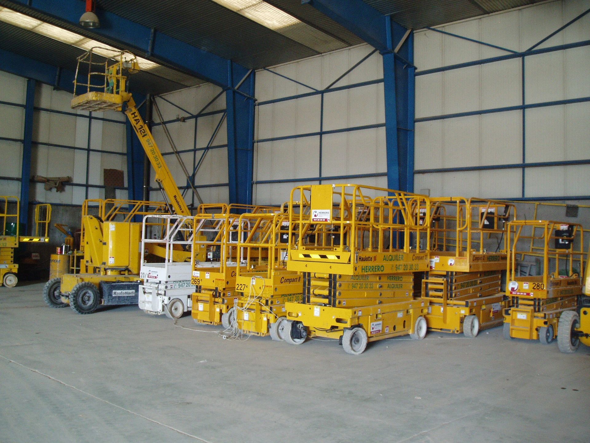 Una fila de elevadores aéreos amarillos en un almacén