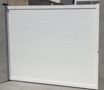 Una puerta blanca está sentada al costado de un edificio.