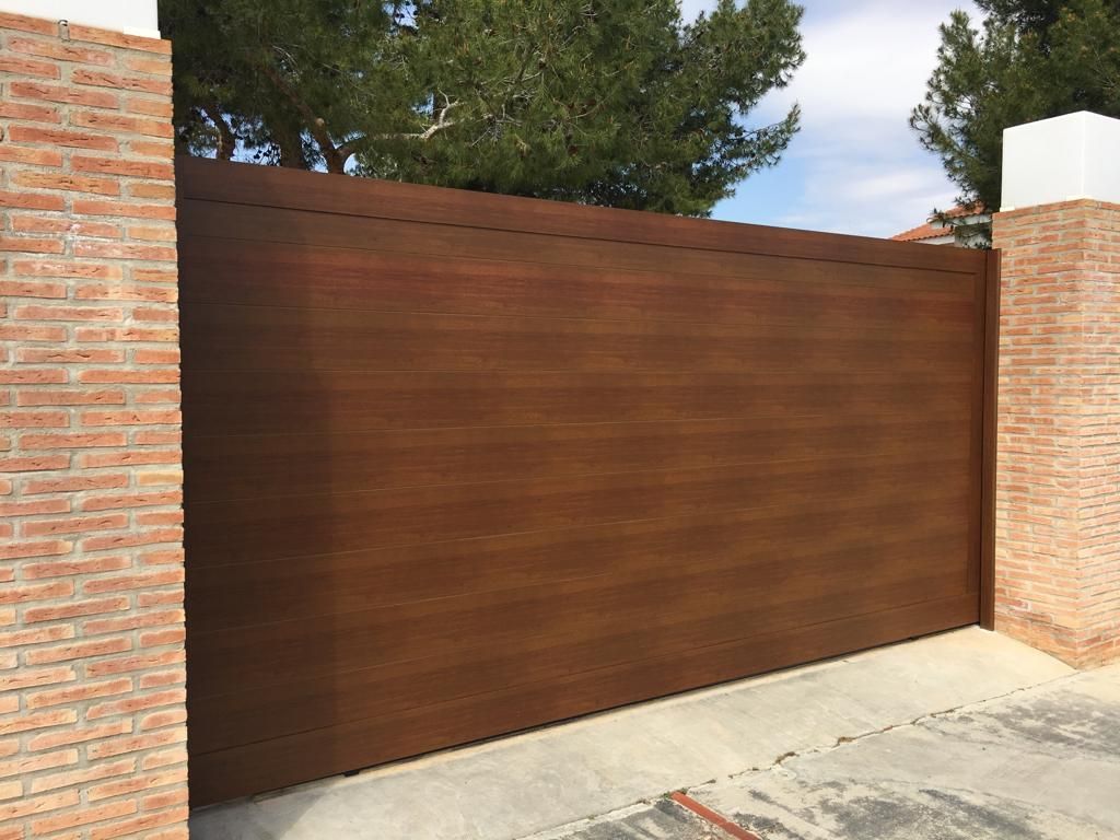 Una gran puerta de madera está al lado de una pared de ladrillos.