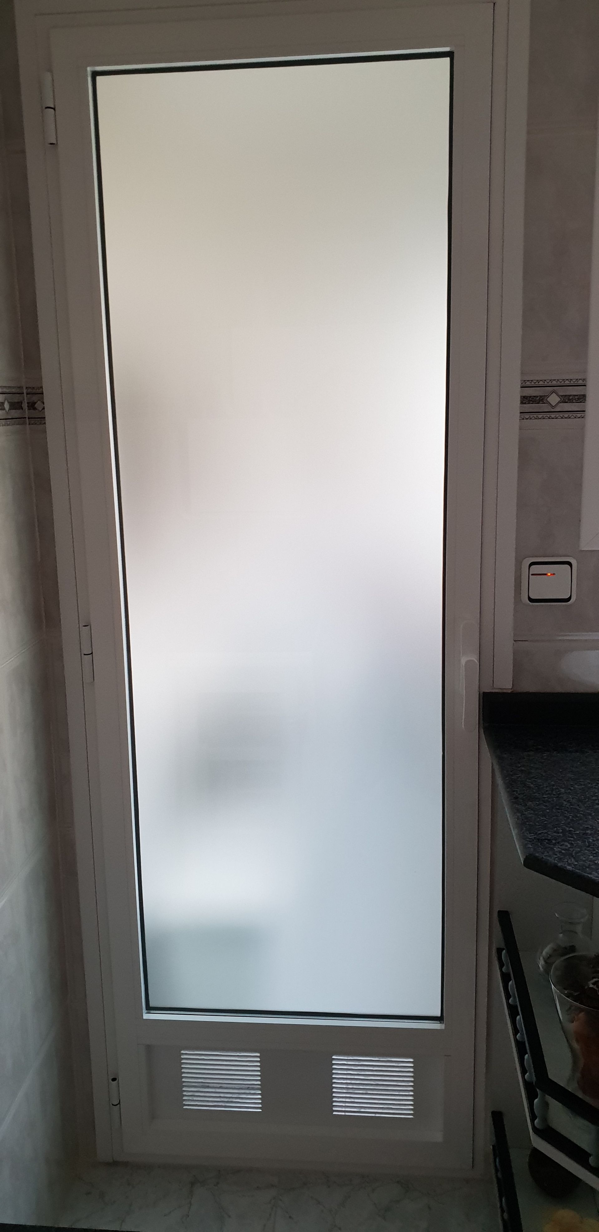 Una puerta blanca con una ventana de vidrio esmerilado en una cocina.