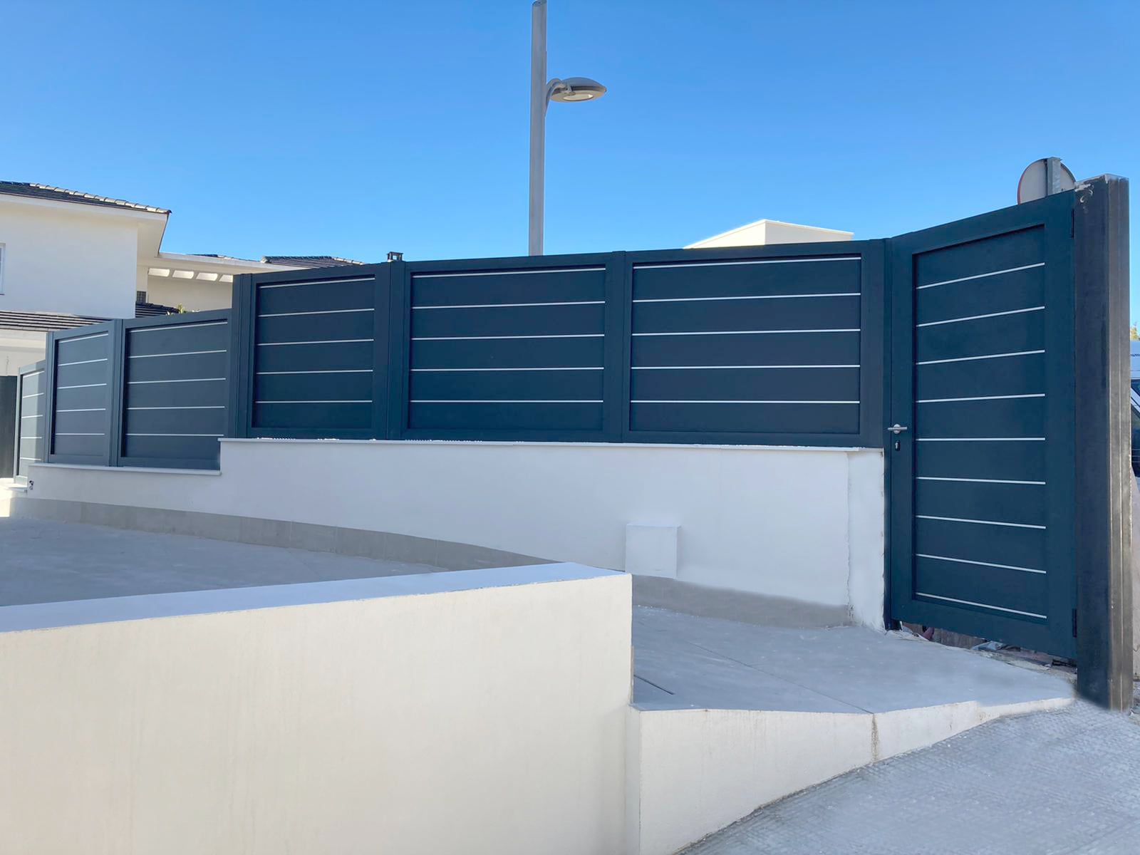 Una pared blanca con una valla negra y una puerta.