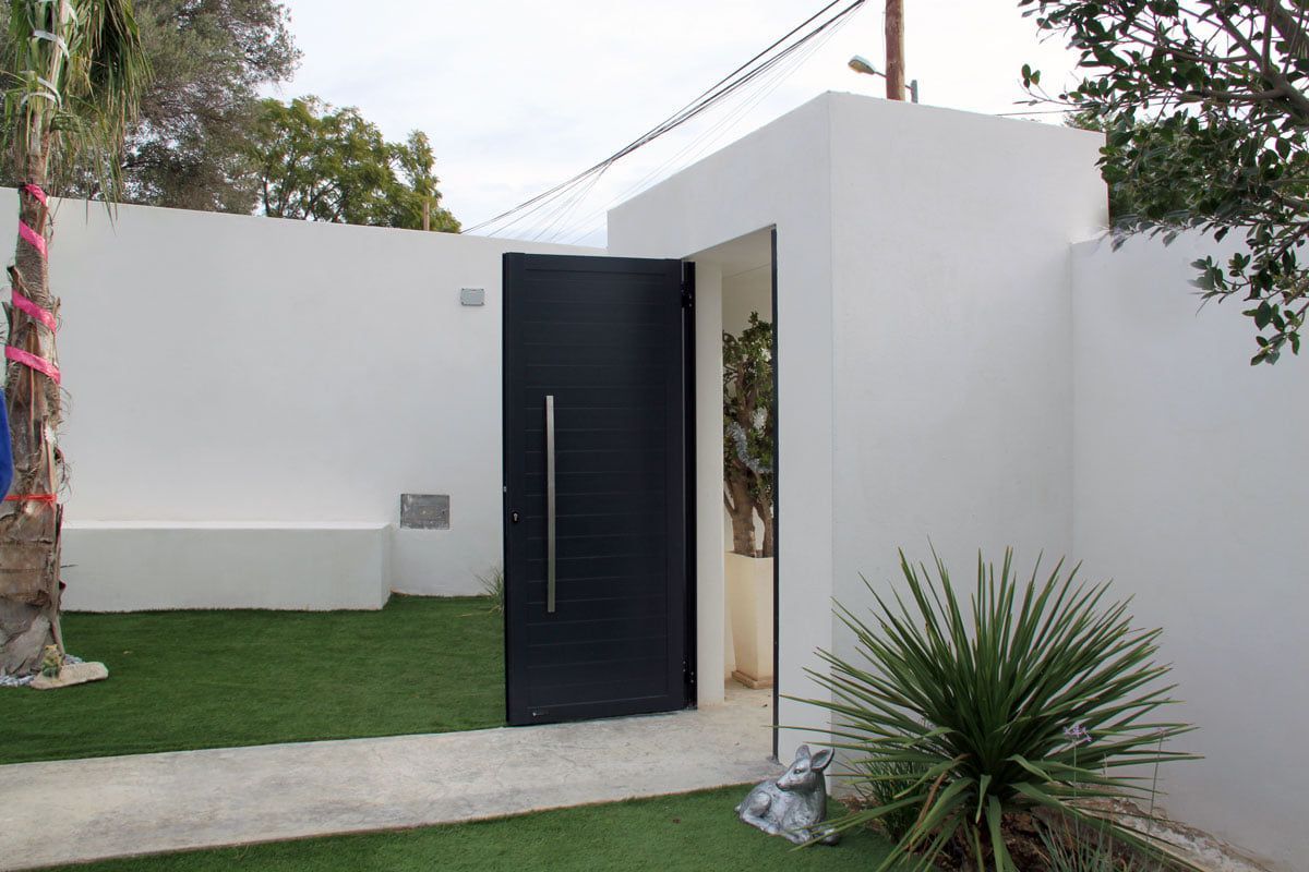 Una puerta negra está abierta a un edificio blanco.