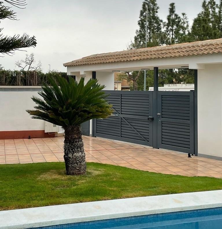 Una palmera se encuentra frente a una valla junto a una piscina.